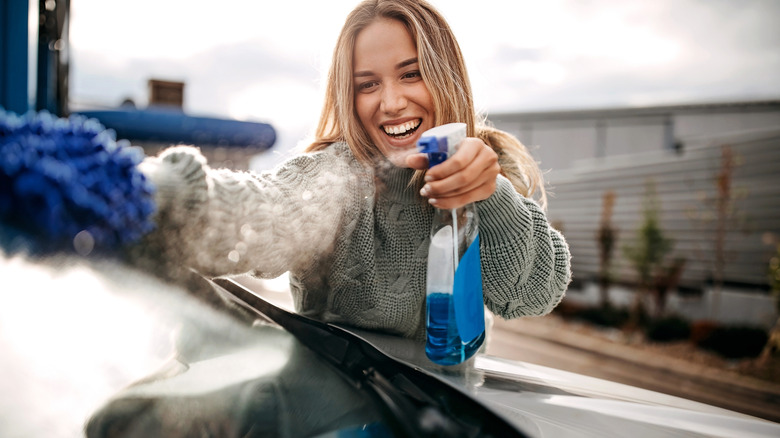 Woman cleaning nan windshield pinch a solid cleaner and microfiber cloth