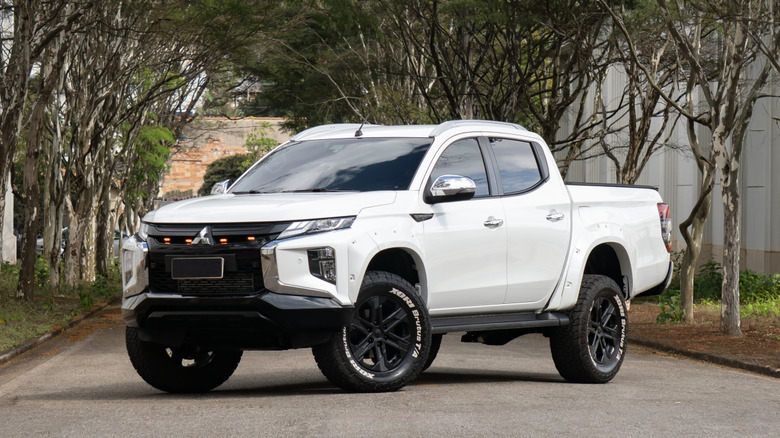 Minas Gerais, Brazil - 27 09 26 - White Mitsubishi L200 Triton Pickup Truck Front Three Quarter View Parked Under Trees