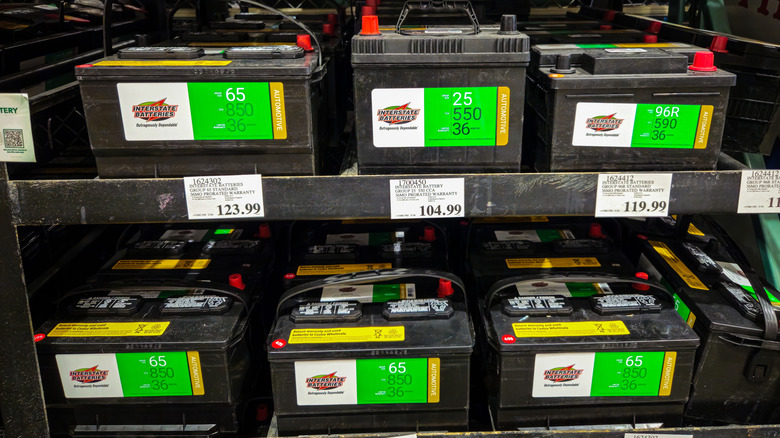 Car batteries with large green and white labels on shelves.