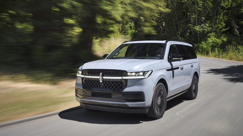 Front 3/4 view of a Grey Mist 2025 Lincoln Navigator Reserve with the Jet Package moving swiftly down a paved road.