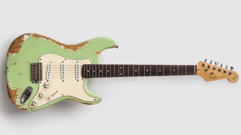 A faded pale green Fender Stratocaster guitar, with portions of the finish worn to the wood.