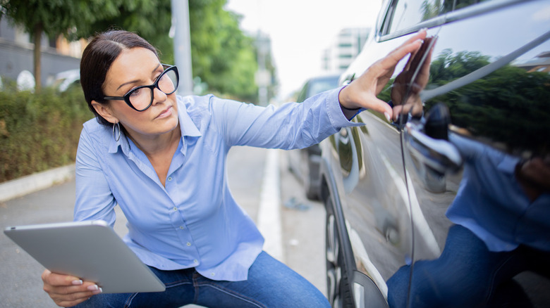 Insurance agent inspects the damage on the car