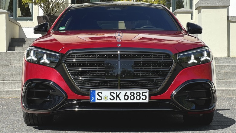 A close-up head-on shot of a red Mercedes-Benz S-Class with a German license plate parked in front of concrete steps