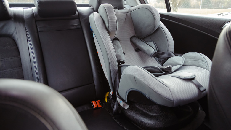 A child car seat secured into the back seat behind the driver