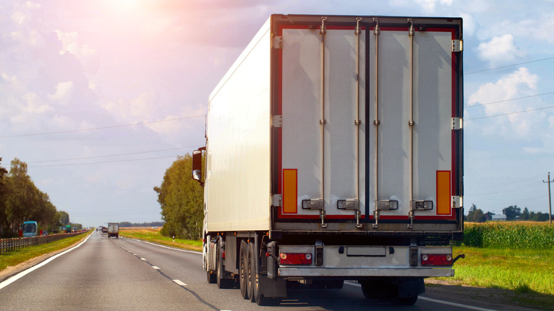 एक ट्रक आसमान और सूरज को देखते हुए राजमार्ग पर चला जा रहा है