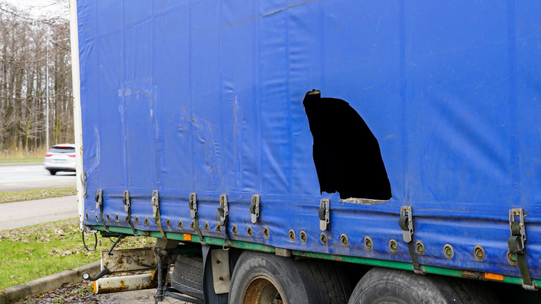 A truck trailer with a blue damaged awning