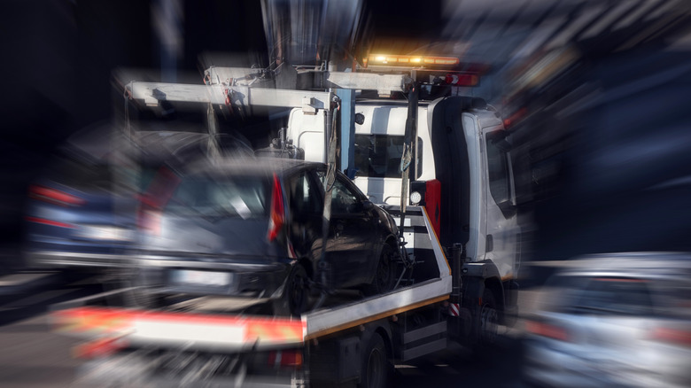 Tow truck carrying improperly parked car or repossessed vehicle.