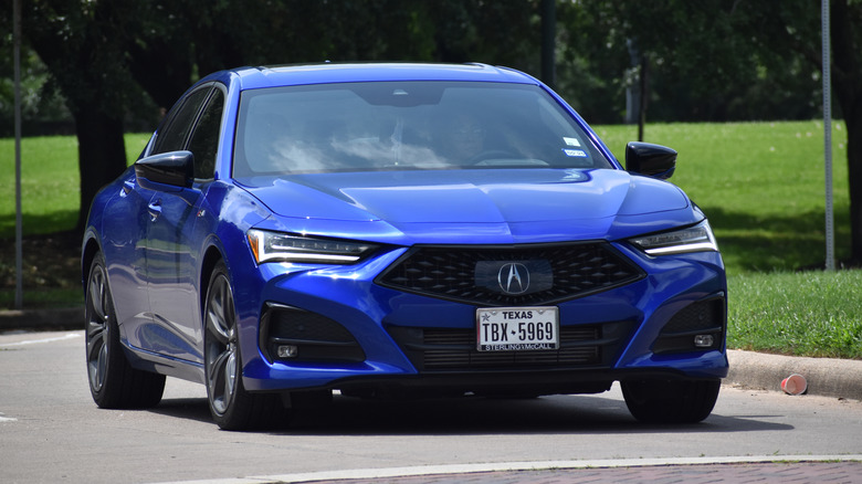 A blue Acura TLX sits parked near a cup on the ground.
