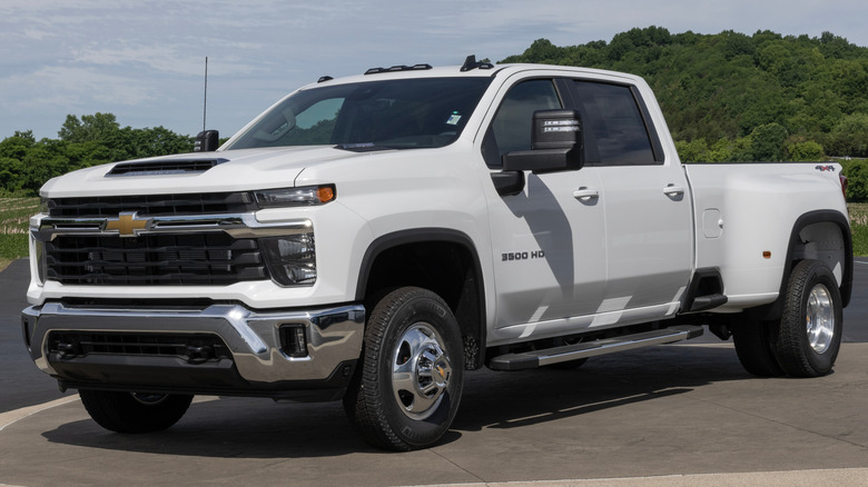 A Chevrolet Silverado 3500 sits parked in front of trees and grass.