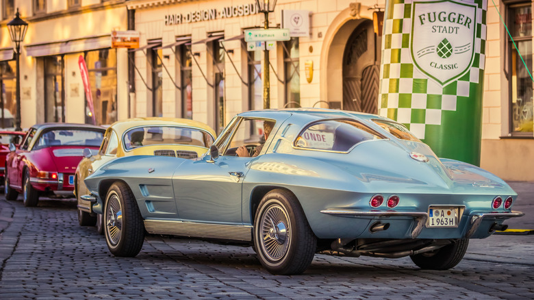 The rear left 3/4 of a silver 1969 Chevrolet Corvette Sting Ray Split Window on a busy street