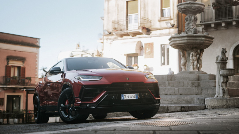a red lamborghini suv parked in an italian square