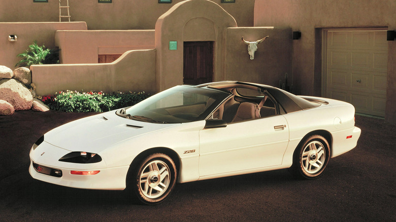 A white 1993 Chevrolet Camaro Z28 convertible parked near a house