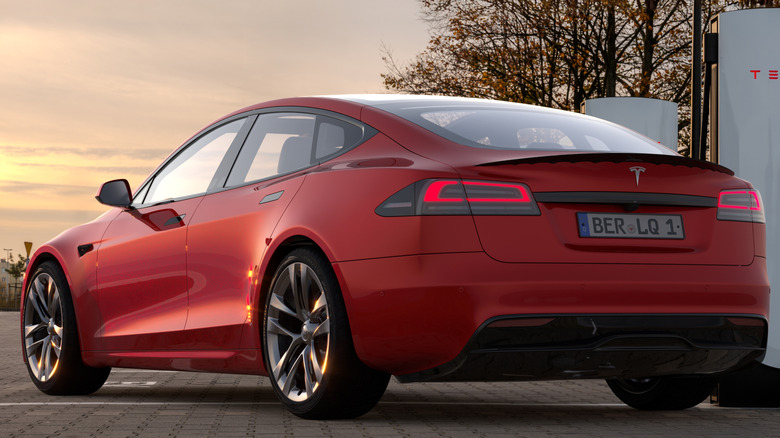 A red Tesla Model S Plaid parked near chargers