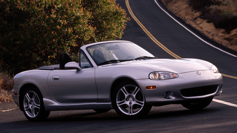 A silver 2004 Mazda Miata parked on a road.