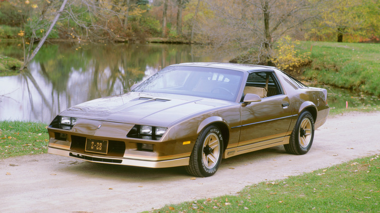 A gold and brown 1982 Chervolet Camaro Z/28 on a pathway.