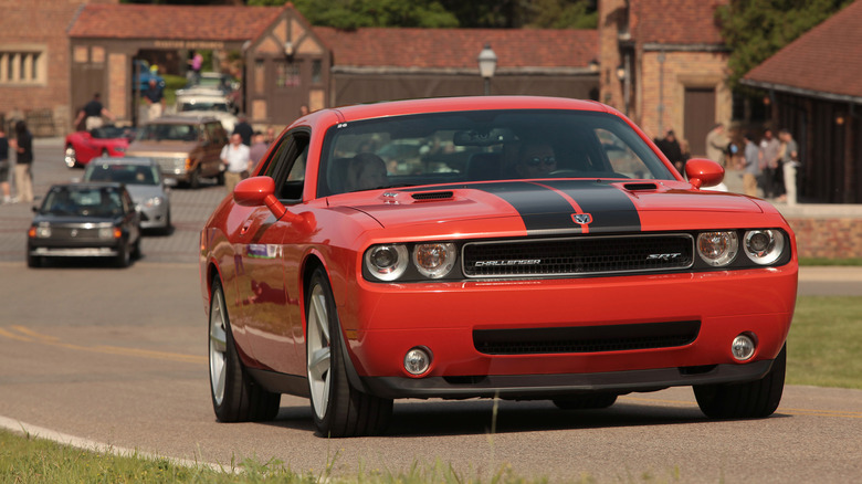 An orange 2008 Dodge Challenger SRT-8 driving down a road.