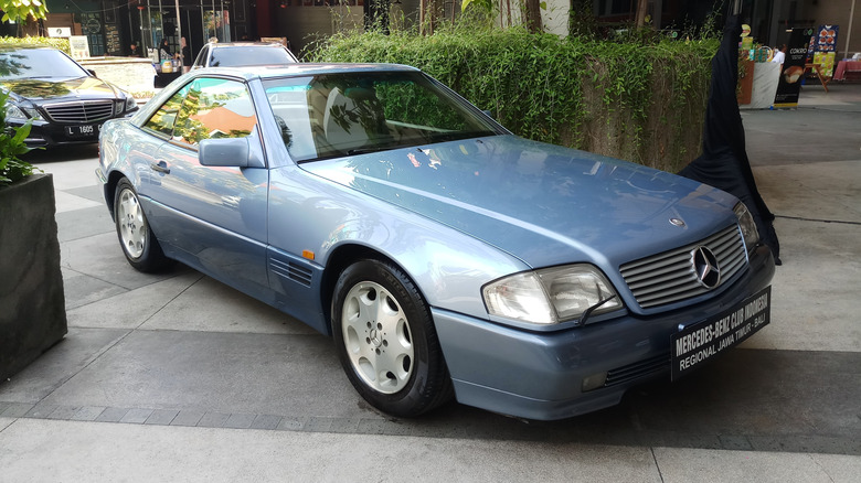 A blue R129 Mercedes-Benz 500SL parked in an urban area.