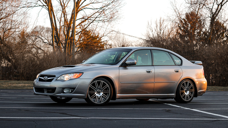 A silver Subaru Legacy GT 2.5 parked in a parking lot during sunset.
