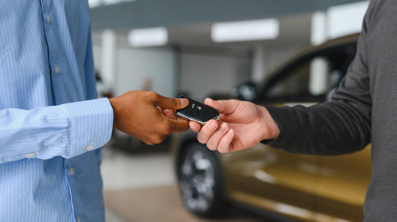 Two people handling a car key at a dealership.