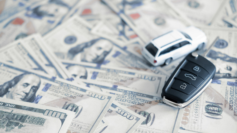 A toy car and car key atop $100 bills