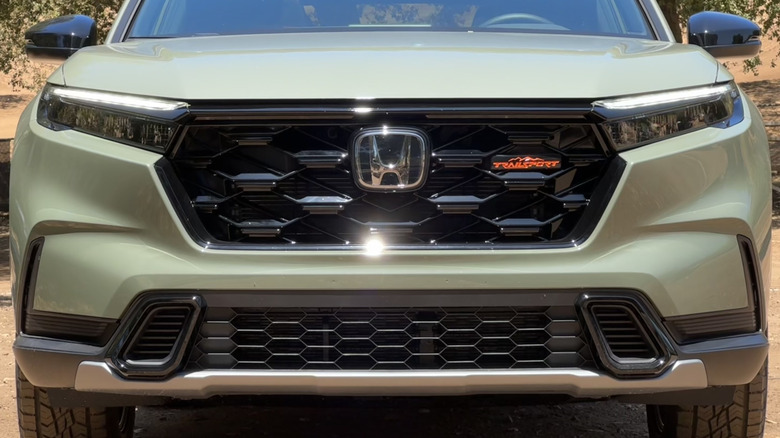 a close-up of a green CR-V Trailsport with the sun glinting off the Honda emblem that hides the radar sensor