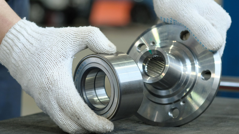 The bearing and wheel hub are in the hands of an auto mechanic.