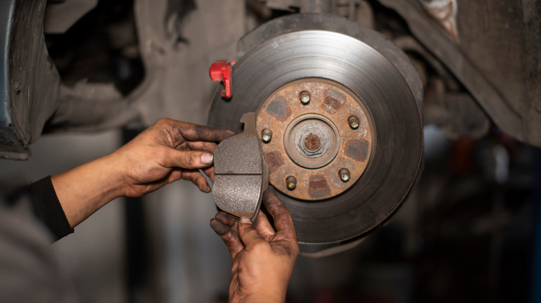 A mechanic showing a used brake pad next to the brake rotor