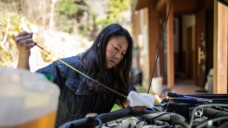 A person using an engine oil dipstick to check their car's engine oil