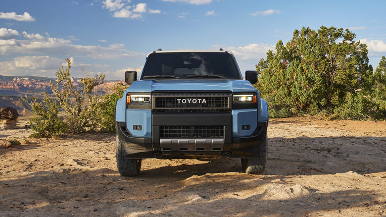 A blue Toyota Land Cruiser is photographed from the front in wild terrain.