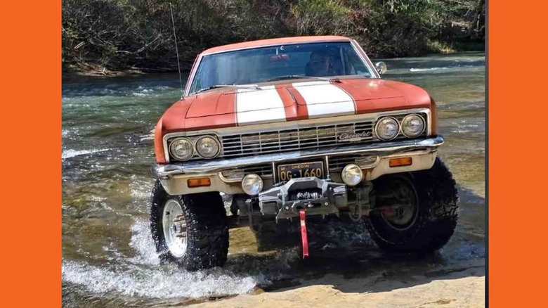 A lifted Chevy Impala drives through a river