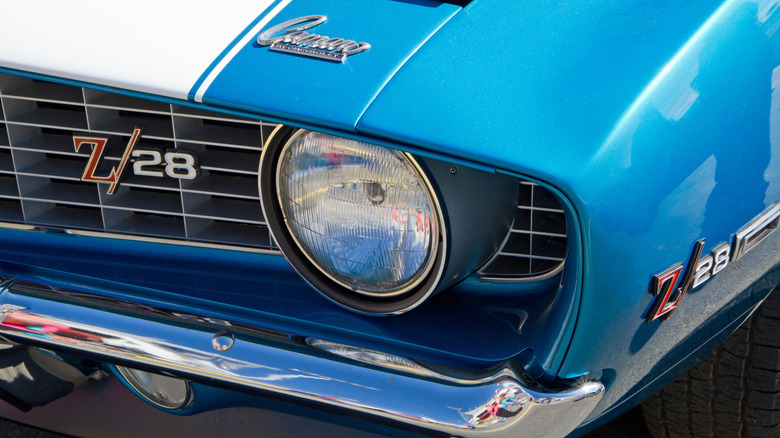 A closeup of a blue and white striped 1968 Chevrolet Camaro Z/28's front left headlight and grille