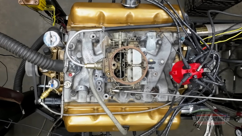 An overhead view of an Oldsmobile W-31 350 V8 with an aluminum intake and gold-painted valve covers on a dyno