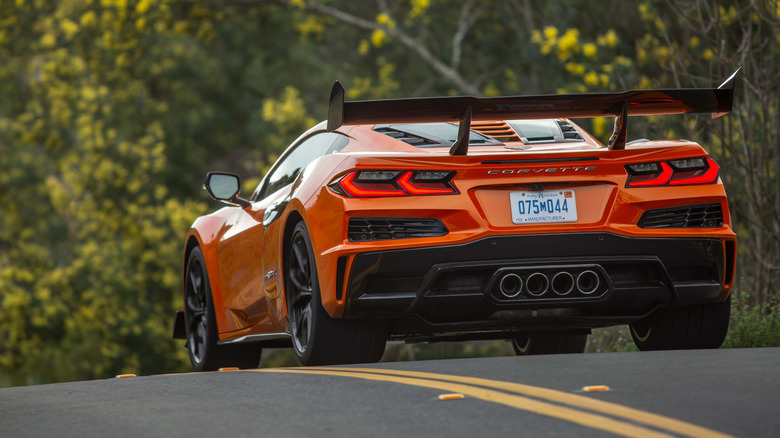 Rear view of an orange 2026 Chevrolet Corvette ZR1X on a road through a forest