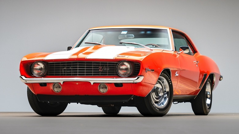 A red 1969 Chevrolet Camaro Z/28 with white stripes against a gray background
