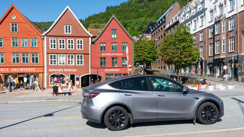 Bergen, Norway - July 9, 2024: Tesla Model Y parked near historic Bryggen wooden houses