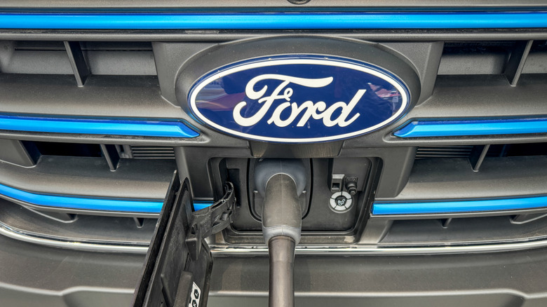 The logo of the Ford Motor Company is displayed on the front grille of a Ford Transit electric van that is being charged on August 4, 2025 in Bristol, England.