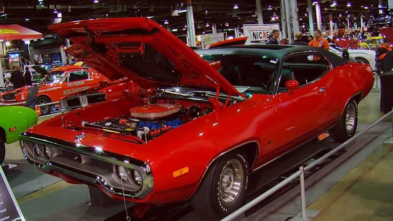 A red 1972 Road Runner V-code muscle car with a 440 V8 with its hood up at a car show