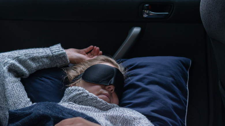 A woman sleeping in the back seat of her car