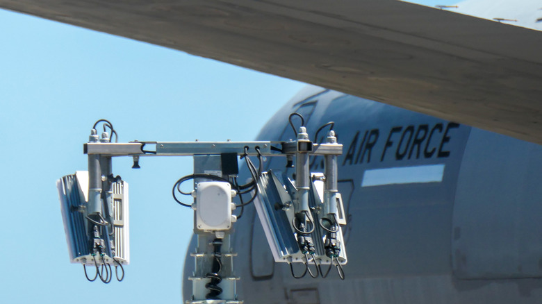 The forward fuselage and insignia of a United States Air Force McDonnell Douglas KC-10A Extender plane, registration 84-0191, parked at Sydney Kingsford-Smith Airport. In the foreground is a portable communications tower and one of the plane's horizontal stabilisers.
