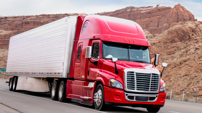A Class 8 semi truck on a four-lane highway through a desert in Utah