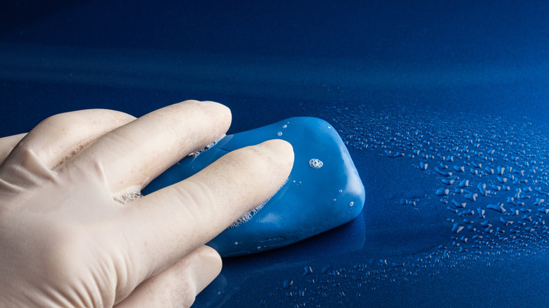 A blue clay bar being used on a car's surface