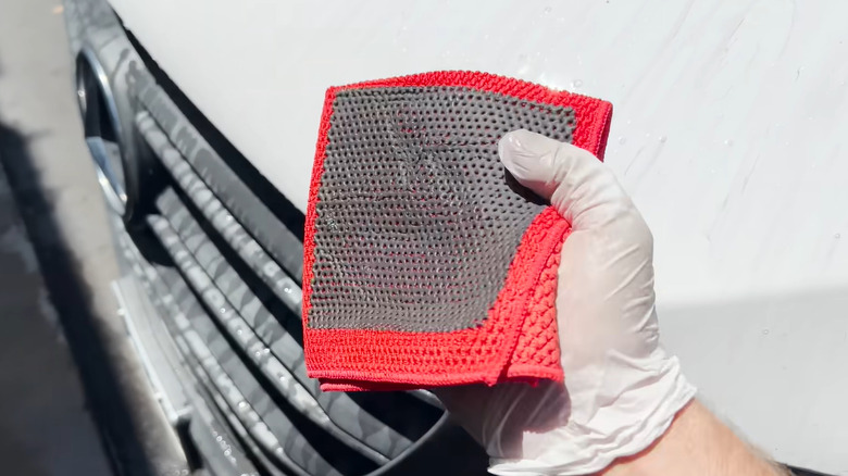 A person holding a clay towel with a gloved hand