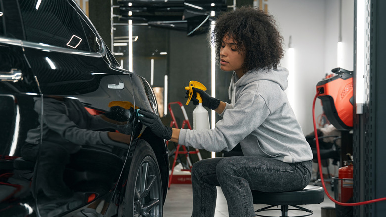 A detailer using a clay bar on a black car
