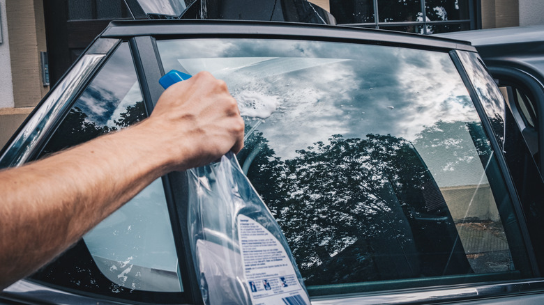 a person using glass cleaner to clean car windows