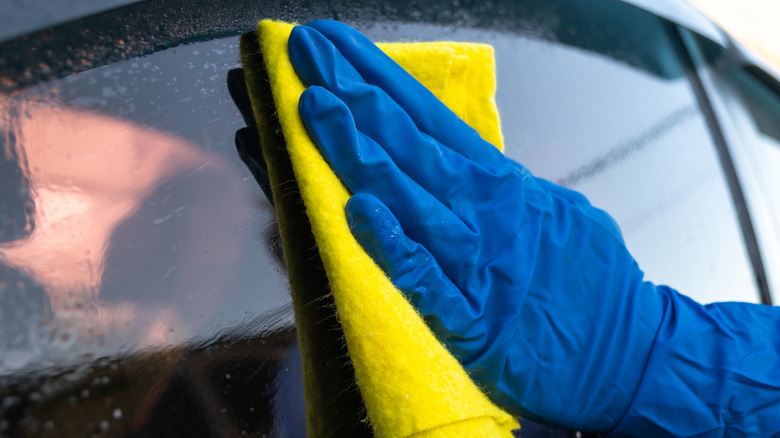 Wiping car window with a microfiber cloth