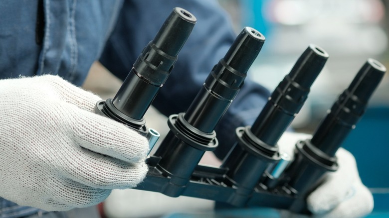 Gloved hands holding a set of ignition coils