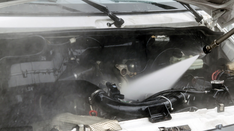 A car engine being blasted by a pressure washer