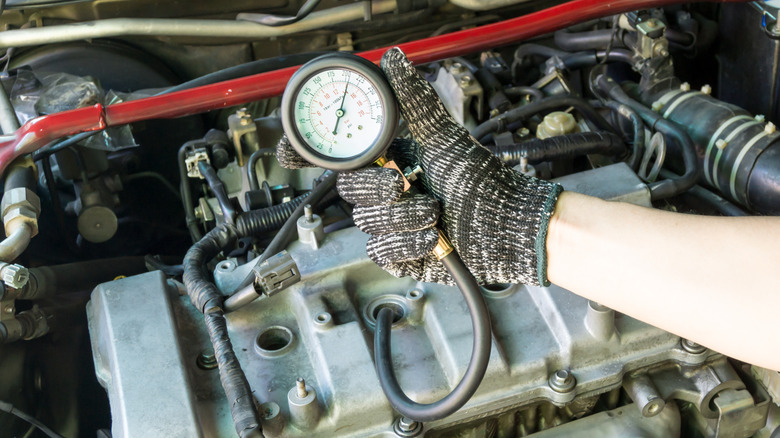 A person using a compression tester to check an engine's compression.