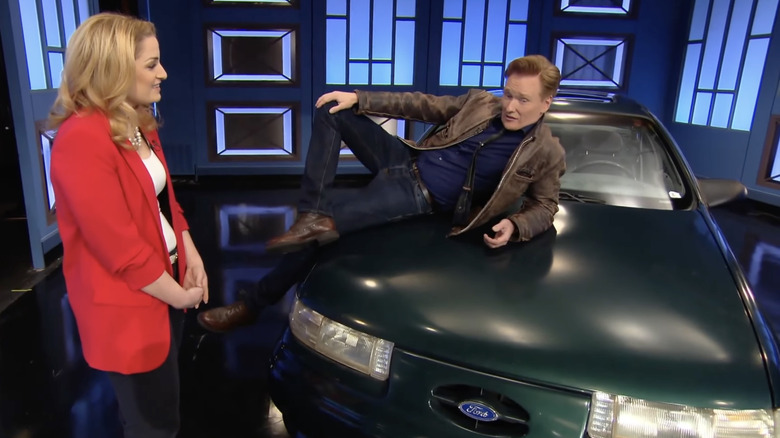 Conan O'Brien poses on the hood of his 1992 Ford Taurus SHO