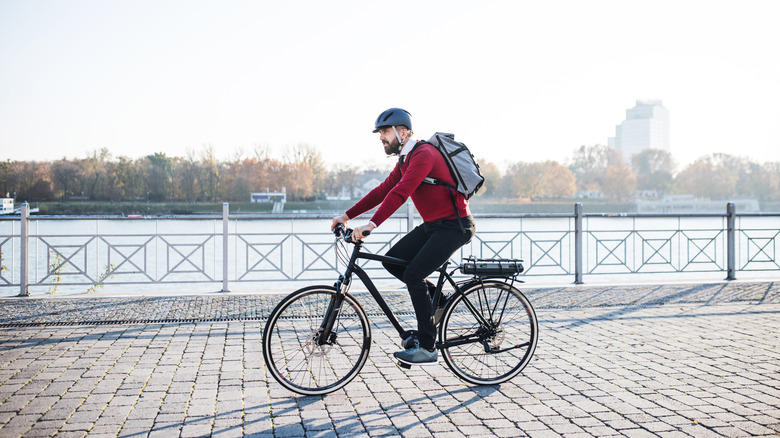 A man riding an e-bike on a paved river walk